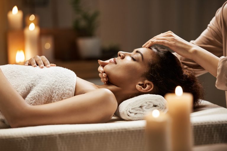 Mulher recebendo massagem no rosto em um ambiente acolhedor e relaxante