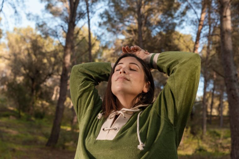 Pessoa em momento de pausa consciente em um ambiente harmonioso e natural, representando a prática do autocuidado e equilíbrio mental.